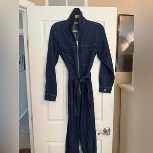 Cubus Denim Jumpsuit
Long Sleeve
Pockets
Zipper
Tie Belt
Size Small